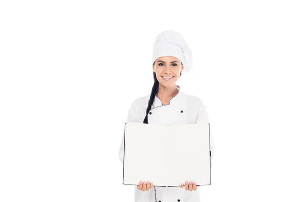 Улыбающийся шеф-повар в шляпе держит открытую книгу изолированной на белом — стоковое фото