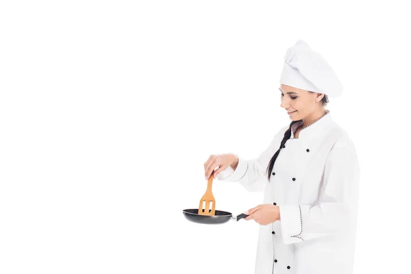 Chef en sombrero sosteniendo sartén y espátula de cocina de madera aislada en blanco - foto de stock
