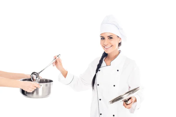 Chef sonriente sumergiendo cucharón en olla aislado en blanco - foto de stock