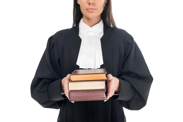 Vue recadrée d'un juge sérieux en robe judiciaire tenant des livres isolés sur blanc — Photo de stock