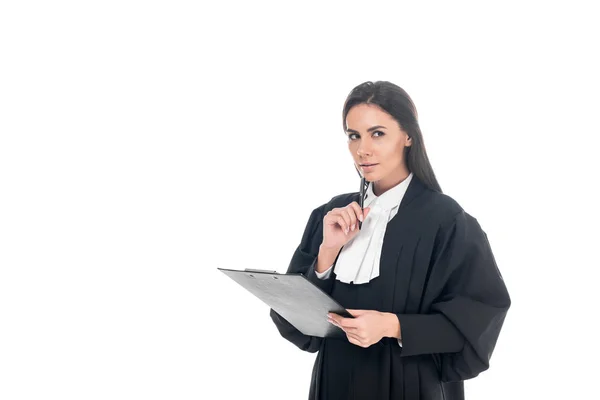 Juez pensativo en bata judicial sujetando portapapeles y bolígrafo aislado en blanco - foto de stock