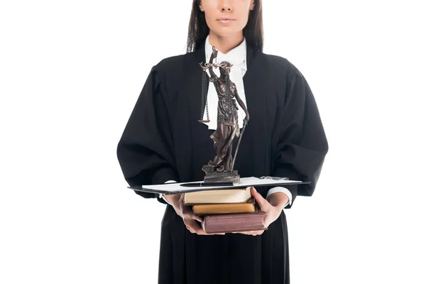 Vista recortada del juez en bata judicial sosteniendo themis estatuilla, libros y portapapeles aislados en blanco - foto de stock