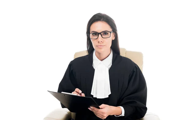Judge sitting in armchair and holding clipboard isolated on white — Stock Photo