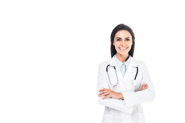 Smiling doctor in white coat standing with folded arms isolated on white — Stock Photo