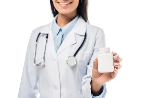 Обрезанный вид врача в белом халате со стетоскопом, держащим таблетки изолированы на белом — стоковое фото
