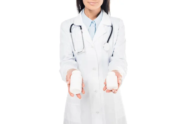 Ausgeschnittene Ansicht eines Arztes im weißen Kittel mit Stethoskop, das Tabletten isoliert auf Weiß hält — Stockfoto