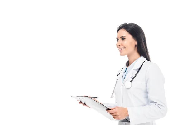 Médico sonriente de capa blanca sujetando el portapapeles aislado en blanco - foto de stock