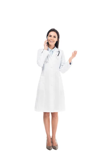 Full length view of doctor in white coat with stethoscope talking on smartphone isolated on white — Stock Photo