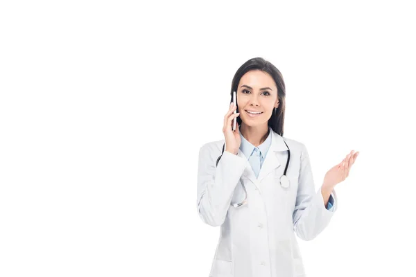 Doctor en bata blanca con estetoscopio hablando en smartphone aislado en blanco - foto de stock