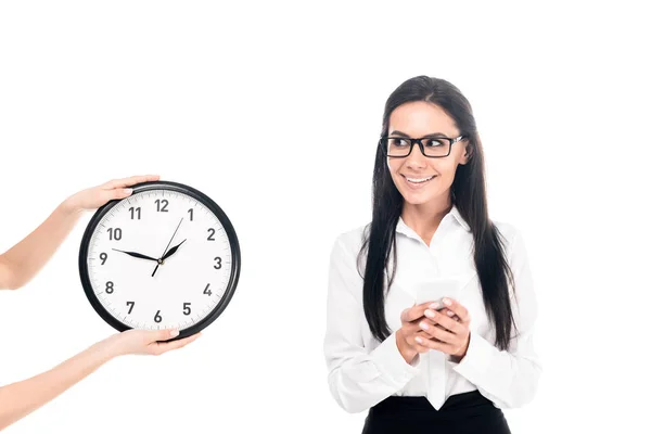 Lächelnde Geschäftsfrau mit Brille, die neben der Uhr steht, isoliert auf weißem Grund — Stockfoto