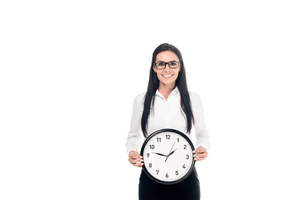 Feliz morena empresaria en camisa sosteniendo reloj aislado en blanco - foto de stock