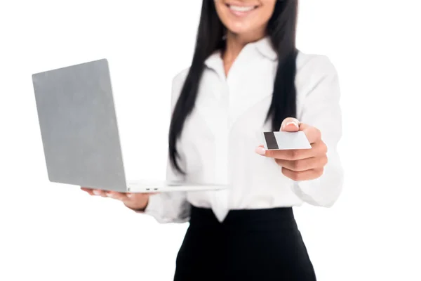 Vue recadrée de femme d'affaires élégante dans des lunettes tenant ordinateur portable et carte de crédit isolé sur blanc — Photo de stock