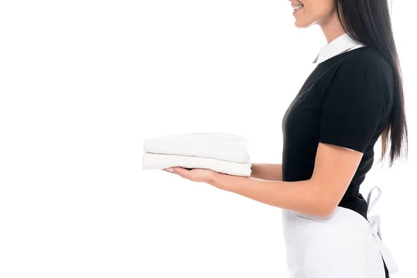 Vista cortada de empregada sorridente em toalhas de segurando uniforme isolado em branco — Fotografia de Stock
