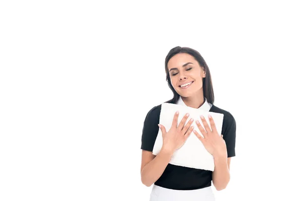 Smiling maid in uniform holding towels isolated on white — Stock Photo