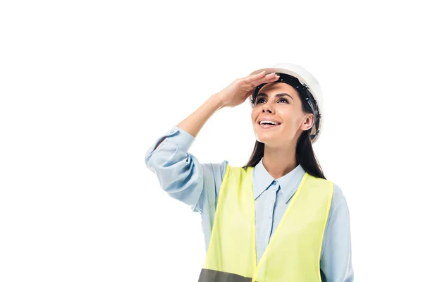 Ingeniero sonriente en chaleco de seguridad y hardhat mirando hacia arriba aislado en blanco - foto de stock