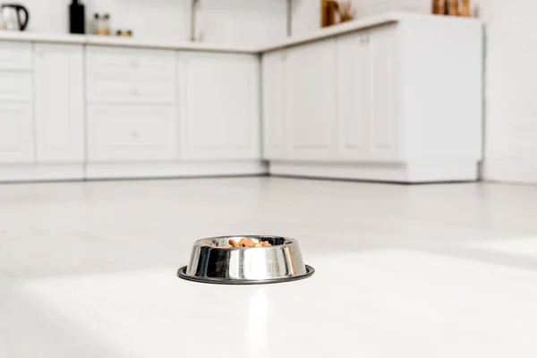 Metal bowl with dog food on white floor in kitchen — Stock Photo