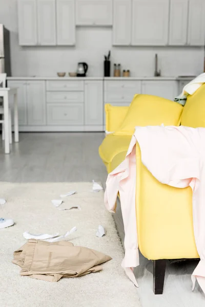 Tapete e sofá amarelo brilhante com panos e papéis — Fotografia de Stock