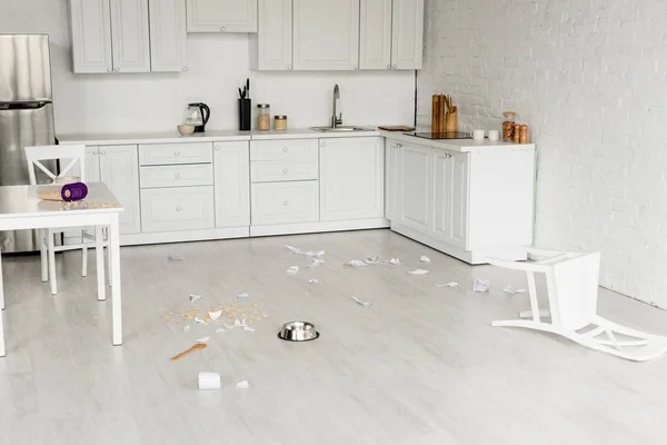 Intérieur de la cuisine avec bol en métal, cuillère en bois et vaisselle cassée sur le sol — Photo de stock