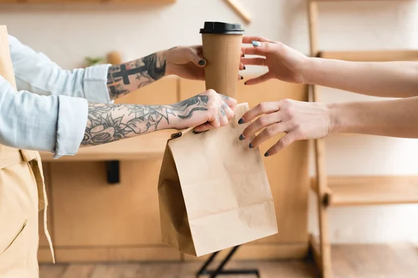 Partial view of waitress giving disposal cup and paper bag to customer — Stock Photo