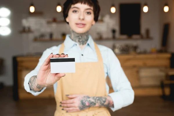 Вибірковий фокус офіціантки тримає кредитну картку і дивиться на камеру — стокове фото