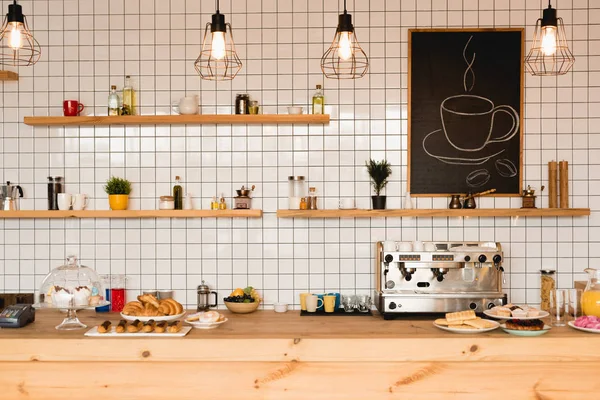 Interno della caffetteria con bancone bar in legno, mensole e parete piastrellata — Foto stock