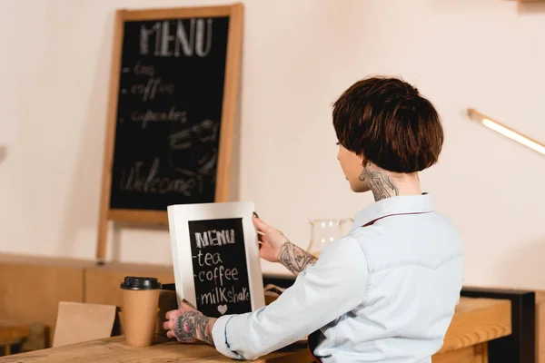 Barista colocando placa com menu manuscrito no balcão de bar no café — Fotografia de Stock