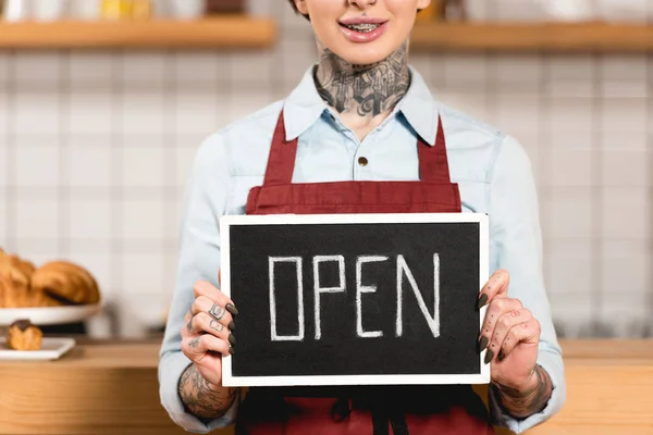 Partial view of barista holding signboard with open inscription in coffee shop — Stock Photo