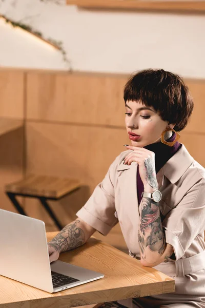 Belle femme d'affaires en utilisant un ordinateur portable tout en étant assis à la table dans un café — Photo de stock