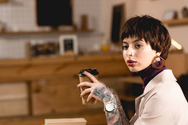 Nachdenkliche Geschäftsfrau sitzt im Café und hält Pappbecher in der Hand — Stockfoto