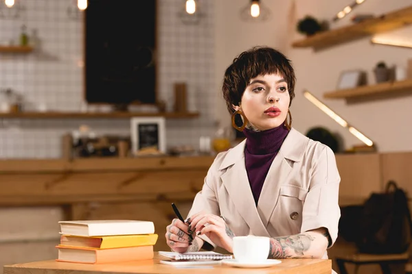 Séduisante et sérieuse femme d'affaires assise à table à la cafétéria — Photo de stock