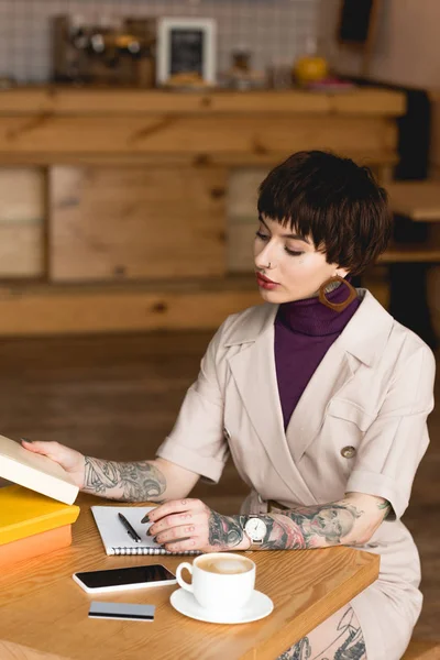 Femme d'affaires à la mode et concentrée assise à table dans un café — Photo de stock