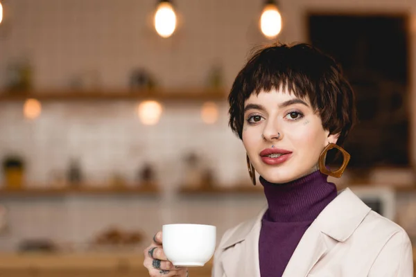 Beautiful businesswoman holding coffee cup, smiling and looking at camera — Stock Photo