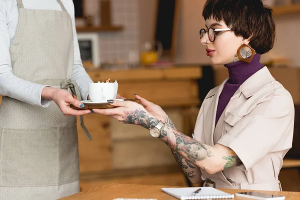 Pretty businesswoman taking tray from waitress in coffee shop — Stock Photo