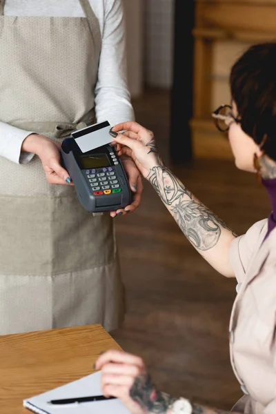 Focalizzazione selettiva della donna d'affari in possesso di carta di credito vicino alla cameriera con terminale di pagamento — Foto stock