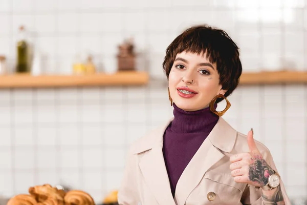 Sonriente, bastante mujer de negocios mostrando el pulgar hacia arriba y mirando a la cámara - foto de stock