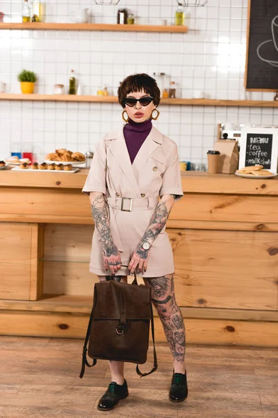 Attraente, donna d'affari alla moda in occhiali da sole in piedi al bancone del bar in caffetteria — Foto stock