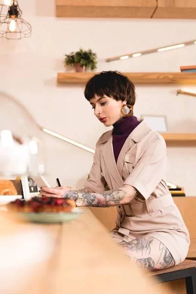 Selektiver Fokus der hübschen Geschäftsfrau, die an der Theke im Café sitzt — Stockfoto