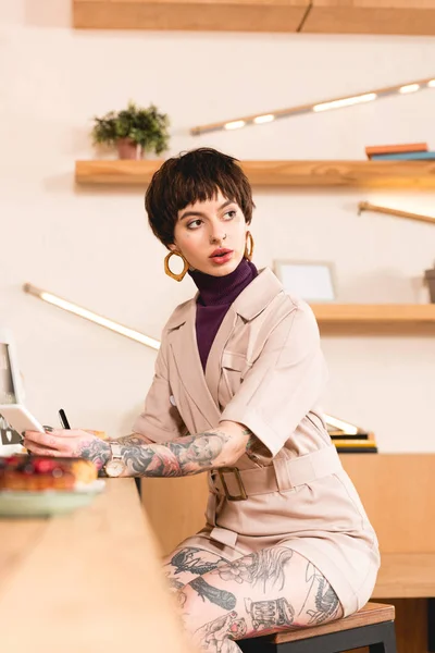Selektiver Fokus seriöser Geschäftsfrau sitzt an der Theke in der Cafeteria — Stockfoto