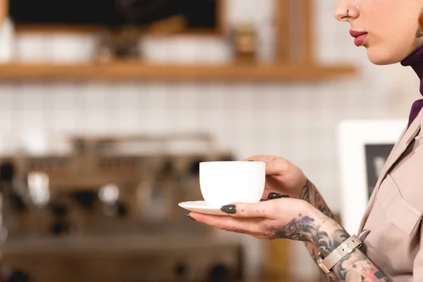 Частковий вид татуйованої бізнес-леді тримає чашку кави в кафе — стокове фото