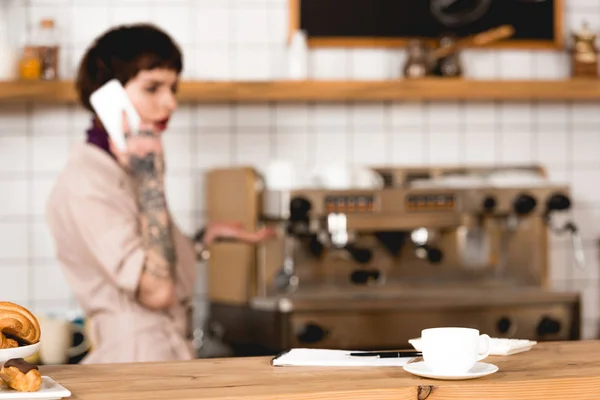 Selektiver Fokus der Geschäftsfrau, die im Coffeeshop mit dem Smartphone spricht — Stockfoto