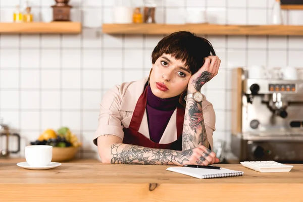 Attractive, tired barista standing at bar counter in coffee shop — Stock Photo