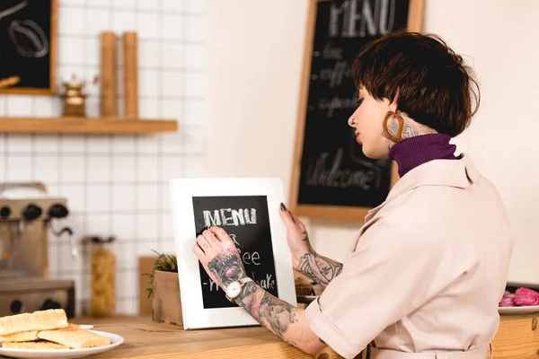 Bonita mujer de negocios escribiendo en el tablero de menú mientras está de pie en el mostrador del bar - foto de stock