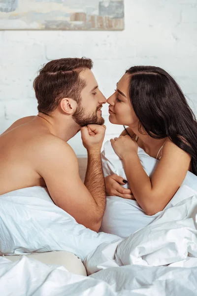 Schöner und muskulöser Mann und schöne Frau schauen einander im Schlafzimmer an — Stockfoto