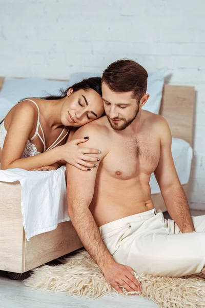 Приваблива жінка в мереживному бюстгальтері обіймає гарний і сексуальний чоловік, сидячи на килимку — стокове фото
