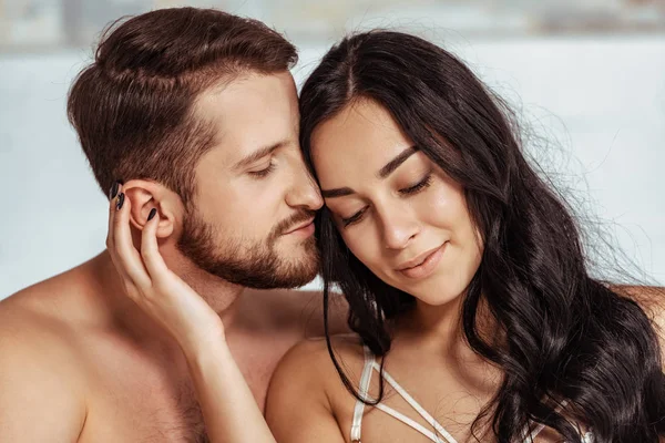 Brunette and beautiful woman hugging good-looking man in bedroom — Stock Photo