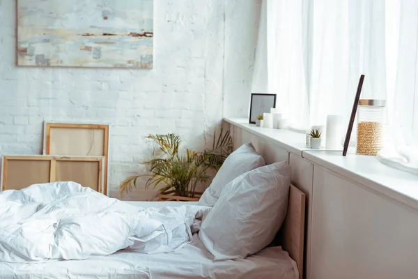 Chambre moderne avec lit confortable, oreillers, couverture, photos et plantes — Photo de stock