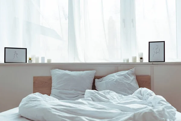 Quarto moderno com cama acolhedora, travesseiros, cobertor, fotos durante o dia — Fotografia de Stock