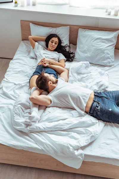 Schöner Mann in Jeans und schöne Frau an der Hand im Schlafzimmer — Stockfoto