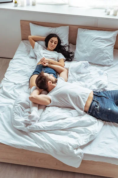 Hombre guapo en jeans y hermosa mujer cogida de la mano en el dormitorio - foto de stock