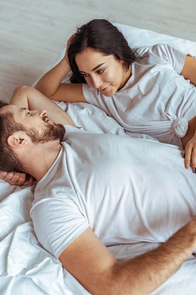 Hombre guapo y hermosa mujer acostada en la cama y mirándose — Stock Photo